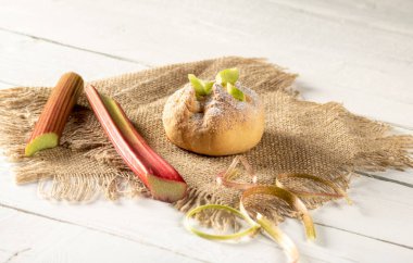 Rubarb çöreği ve ravent sapı tahta bir masanın üzerinde çuval bezi gibi duruyor..