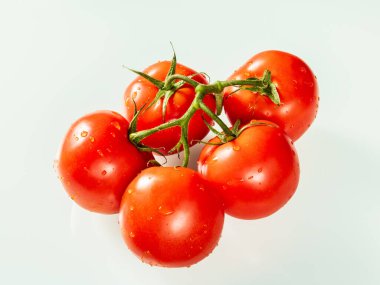 Beyaz zemin üzerinde su damlaları olan büyük kırmızı domatesler..