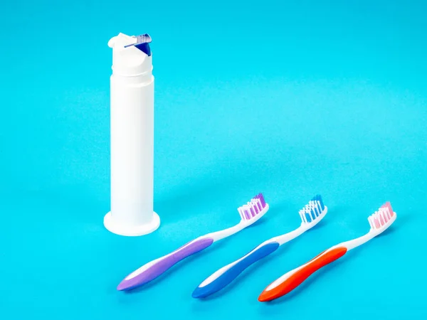Three Multi Colored Toothbrushes Tube Toothpaste Blue Background — Stock Photo, Image