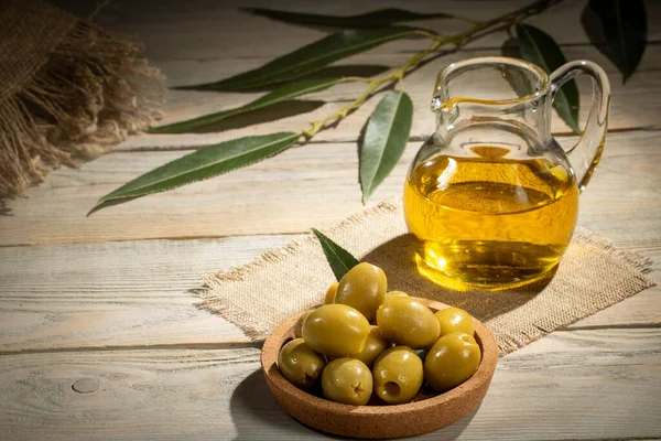 Çuval bezi üzerinde yeşil zeytinyağı ve bir sürahi zeytin yağı..