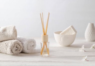 Banyo içi. Yumuşak havlular, bir bardak sabun ve ev parfümü çubuklu bir vazo. Minimalizm tarzı, yüksek tuşlu fotoğraf