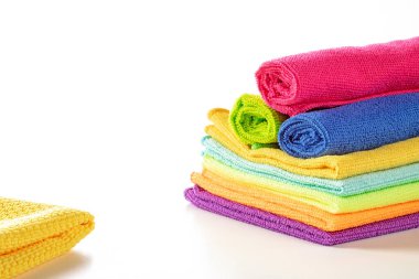 Beyaz arka planda parlak renklerde mutfak mikrofiber havluları yığını. Kapatın, peçeteleri üst tarafa sarın.