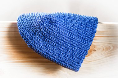 Doğal ahşap bir standın arka planında büyük mavi iplikten örülmüş bir spor şapkası. Hafif vignette