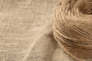 A ball of coarse textured jute threads on a burlap napkin. Close up clipart