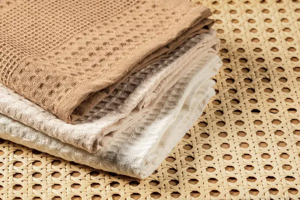 Waffle havluları üst görünümü olan rattan bir paspasın arka planında bir yığın halinde katlanır.