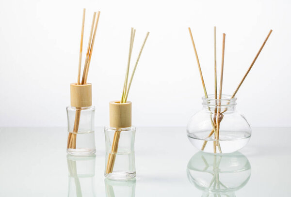 Glass bottles with incense sticks on a white mirror table.