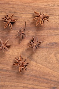 Anasonlu yıldızların doğal ahşap bir zemin üzerine yerleştirilmiş, aromatik ve kırsal bir sahne sunan, mutfak uygulamalarında baharat kullanımını temsil eden bir üst görünüm..