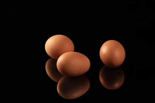 Parlak Siyah Aynalı Bir Yüzey Üzerinde Kahverengi Tavuk Yumurtalarının Yansımasını — Stok fotoğraf
