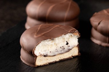 Loş ışıkta karanlık bir yüzeye yerleştirilmiş cazip bir çikolatalı şekerlemenin yakın çekimi karamsar ve büyüleyici bir ortam yaratıyor..