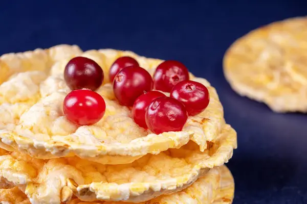 A close-up of delicious homemade corn cakes topped with a colorful arrangement of fresh cranberries, serving as a healthy and visually appealing breakfast option in the morning light.