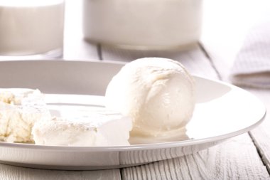 Beyaz tabakta bir bardak süt, süzme peynir ve mozzarella.