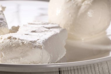 Beyaz tabakta bir bardak süt, süzme peynir ve mozzarella.