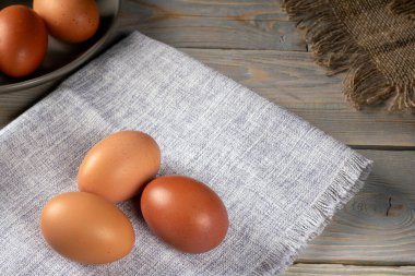 Çok renkli tavuk yumurtalarının canlı bir görüntüsü, doğanın güzelliğini ve çeşitliliğini gösteren ahşap bir masanın üzerinde duruyor. Ekoloji, tarım ve taze üretim temaları için ideal.