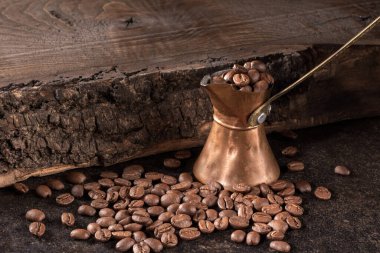 Zengin kahve çekirdekleri ile dolu zarif bir antika bakır kahve makinası, kırsal ahşap bir arka plana kurulmuş. Kahve meraklıları ve klasik dekoratörler için mükemmel..