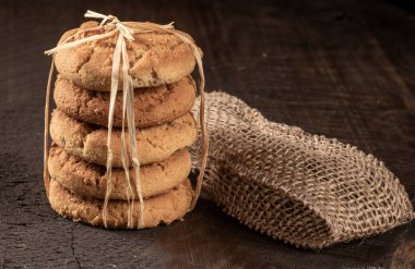 Taze pişmiş kuru üzümlü kurabiyelerin enfes bir yayılımı kırsal bir masa üzerinde sergileniyor, büyüleyici bir dekor ile çevrili. Sıcak renkler ve davetkar atmosfer rahat bir ortam yaratır..