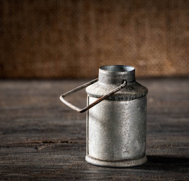 Eski, antika bir süt kutusu ahşap bir masaya konmuş, nostalji hissi uyandırıyor. Çiftlik evi dekorasyonu, kırsal yaşam veya tarım mirası temaları için mükemmel..