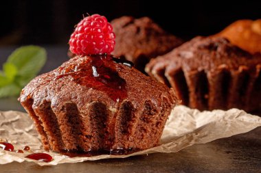 Savor the charm of yummy muffins and fresh raspberries beautifully arranged on a sleek black kitchen table. This image evokes warmth and the joy of homemade treats in a stylish kitchen.