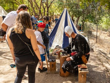 Kudüs, İsrail, 24 Eylül 2022: Ziyaretçiler, İsrail 'in Kudüs kentindeki Ein Yael Müzesi' nde düzenlenen Kudüs Şövalyeleri Festivali katılımcılarının rehberliğinde madeni para basma konusunda açıklama alıyorlar.