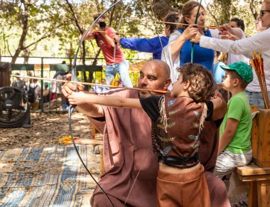 Kudüs, İsrail, 24 Eylül 2022: İsrail 'in Kudüs kentindeki Ein Yael Müzesi' nde düzenlenen festivale katılan bir katılımcının rehberliğinde okçuluk eğitimi alan bir ziyaretçi