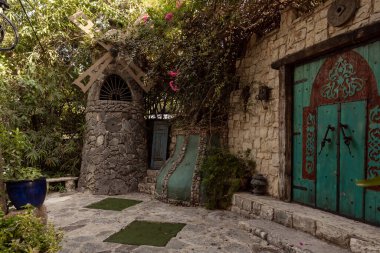 Nahariya, İsrail, 21 Ekim 2022: Dekoratif taş yel değirmeni ve dekoratif ahşap kapı Almona Bahçeleri koleksiyonunda, batan güneşin ışınlarında, İsrail 'in kuzeyindeki Julis Druze köyünde sergilendi