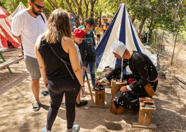 Kudüs, İsrail, 24 Eylül 2022: Ziyaretçiler, İsrail 'in Kudüs kentindeki Ein Yael Müzesi' nde düzenlenen Kudüs Şövalyeleri Festivali katılımcılarının rehberliğinde madeni para basma konusunda açıklama alıyorlar.