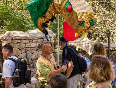 Kudüs, İsrail, 24 Eylül 2022: Ortaçağ elbisesi giymiş bir festival katılımcısı, İsrail 'in Kudüs kentindeki Ein Yael Müzesi' nde elinde büyük bir ejderhayla ziyaretçiler arasında yürüyor.