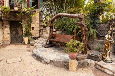 Nahariya, İsrail, 21 Ekim 2022: Dekoratif ahşap bank - Almona Bahçeleri koleksiyonunda sallanan sandalye, batan güneşin ışınlarında, İsrail 'in kuzeyindeki Julis Druze köyünde