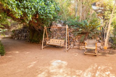 Eilat, Israel, December 13, 2022 : Decorative wooden swing and wooden lounge chair on exposition in the Botanical Garden in the Eilat city, southern Israel
