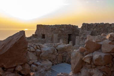 The remains of internal buildings in the rays of the rising sun in the ruins of the fortress of Masada - is a fortress built by Herod the Great on a cliff-top off the coast of the Dead Sea, in southern Israel