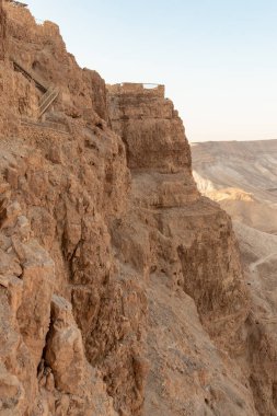 The remains of outer walls in the rays of the rising sun in the ruins of the fortress of Masada - is a fortress built by Herod the Great on a cliff-top off the coast of the Dead Sea, in southern Israel