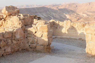 The remains of internal buildings in the rays of the rising sun in the ruins of the fortress of Masada - is a fortress built by Herod the Great on a cliff-top off the coast of the Dead Sea, in southern Israel