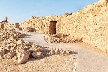 The remains of internal buildings in the rays of the rising sun in the ruins of the fortress of Masada - is a fortress built by Herod the Great on a cliff-top off the coast of the Dead Sea, in southern Israel