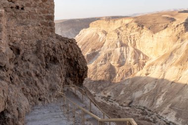 View during sunrise from the ruins of the fortress wall of the fortress of Masada to the ruins of the palace of King Herod and to the adjacent valley, in southern Israel