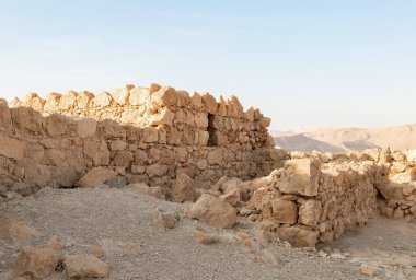 The remains of internal buildings in the rays of the rising sun in the ruins of the fortress of Masada - is a fortress built by Herod the Great on a cliff-top off the coast of the Dead Sea, in southern Israel
