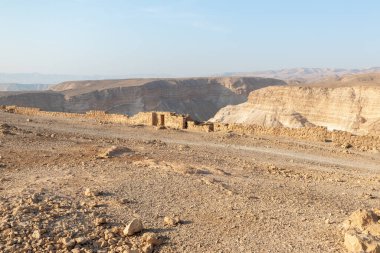 The remains of internal buildings in the rays of the rising sun in the ruins of the fortress of Masada - is a fortress built by Herod the Great on a cliff-top off the coast of the Dead Sea, in southern Israel