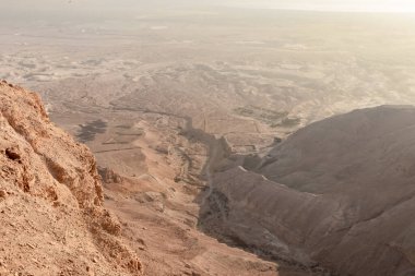 View before sunrise from the ruins of the fortress wall of the fortress of Masada to the remains of a Roman battle camp and the adjacent valley, in southern Israel