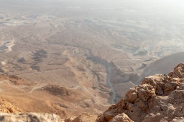 View before sunrise from the ruins of the fortress wall of the fortress of Masada to the remains of a Roman battle camp and the adjacent valley, in southern Israel