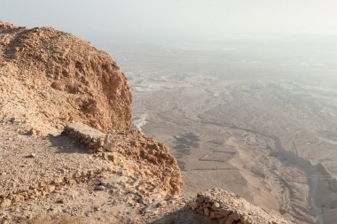 View before sunrise from the ruins of the fortress wall of the fortress of Masada to the remains of a Roman battle camp and the adjacent valley, in southern Israel