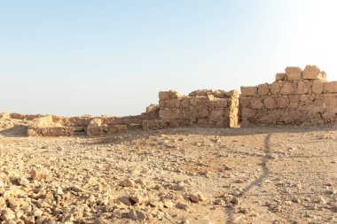 The remains of internal buildings in the rays of the rising sun in the ruins of the fortress of Masada - is a fortress built by Herod the Great on a cliff-top off the coast of the Dead Sea, in southern Israel