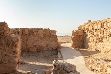 The remains of internal buildings in the rays of the rising sun in the ruins of the fortress of Masada - is a fortress built by Herod the Great on a cliff-top off the coast of the Dead Sea, in southern Israel