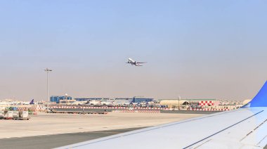 Dubai, Birleşik Arap Emirlikleri, 16 Mart 2023: Pist boyunca ilerleyen bir Flydubai uçağının penceresinden Dünya Havayolları 'nın ayakta duran uçaklarına ve Dubai havaalanı binasına bakın