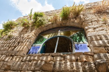 Kuzey İsrail 'in güvenli şehrinin eski bir bölgesinde sakin bir sokakta terk edilmiş taştan eski bir evde büyük bir vitraylı pencere.