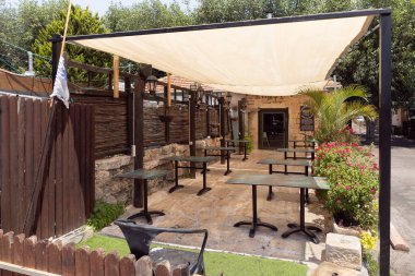 Zikhron Yaakov, İsrail, Temmuz 2023: İsrail 'in kuzeyindeki Zikhron Yaakov şehrinin ana yaya sokağı yakınlarındaki küçük bir sokak restoranının yakınındaki masa ve sandalyelerle güneşli bölgeden kaplandı