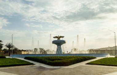 Abu Dabi, Birleşik Arap Emirlikleri, 19 Mart 2023: Birleşik Arap Emirlikleri 'ndeki Abu Dabi meydanındaki dekoratif bir çeşmenin üzerindeki batan güneşin ışınlarında bir turist otobüsünün penceresinden görüntü