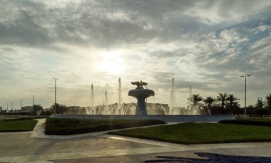 Abu Dabi, Birleşik Arap Emirlikleri, 19 Mart 2023: Birleşik Arap Emirlikleri 'ndeki Abu Dabi meydanındaki dekoratif bir çeşmenin üzerindeki batan güneşin ışınlarında bir turist otobüsünün penceresinden görüntü