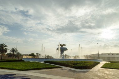 Abu Dabi, Birleşik Arap Emirlikleri, 19 Mart 2023: Birleşik Arap Emirlikleri 'ndeki Abu Dabi meydanındaki dekoratif bir çeşmenin üzerindeki batan güneşin ışınlarında bir turist otobüsünün penceresinden görüntü