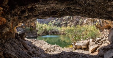 Mağaradan İsrail 'in kuzeyindeki Yehudia Ulusal Doğal Parkı' ndaki ağaçlar ve çalılarla çevrili küçük bir göle bakın.