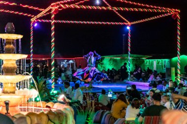 Dubai, Birleşik Arap Emirlikleri, 20 Mart 2023: Sahnedeki dansçı, Dubai 'de, Birleşik Arap Emirlikleri yakınlarındaki kumlu çölde, Macera Gezegeni Turizminde geleneksel Arap performansını sergiliyor.