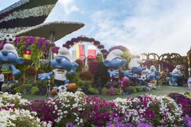 Dubai, Birleşik Arap Emirlikleri, 21 Mart 2023: Dubai, Birleşik Arap Emirlikleri 'ndeki botanik Dubai Mucize Bahçesi' nde düzenlenen Dünya Kupası milli futbol takımlarının kıyafetleri içinde büyük Şirinler bebekleri