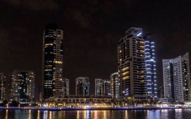 Dubai, Birleşik Arap Emirlikleri, 21 Mart 2023: Dubai limanından gece manzarası aydınlık gökdelenler, bir su kanalı, yatlar ve gemiler Dubai şehrinde, Birleşik Arap Emirlikleri
